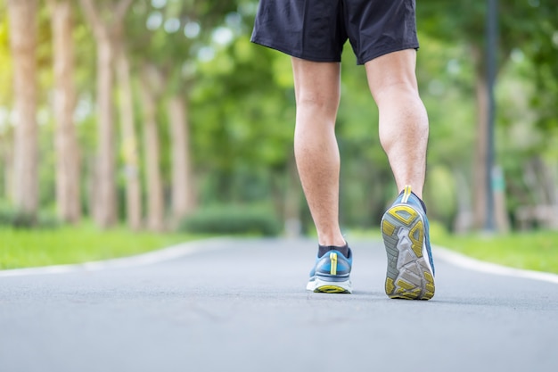 Varón adulto joven en calzado deportivo corriendo en el parque al aire libre