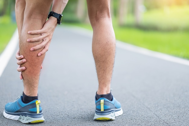 Varón adulto joven con su dolor muscular durante la carrera