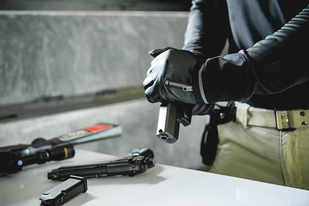 Varón asiático con guantes de cuero negro con pistola en balas de carga manual para pistola