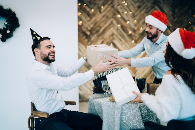 Varón barbudo que recibe el regalo de Navidad de un amigo