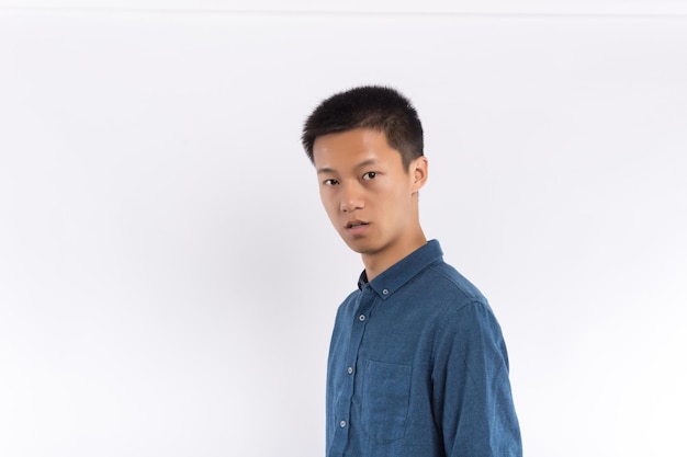 Varón hermoso joven en camisa azul delante de un fondo blanco