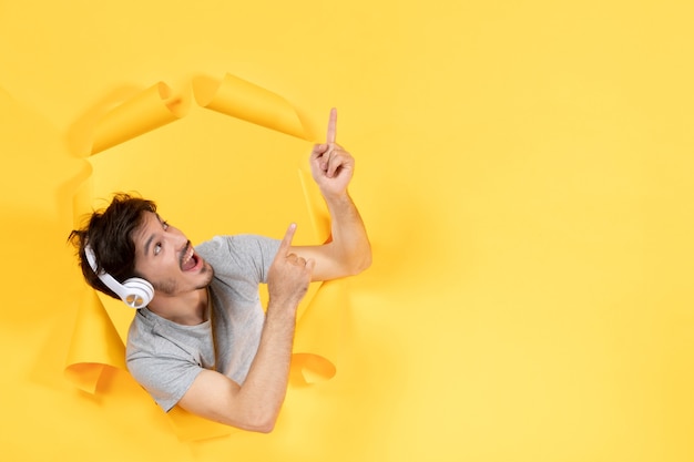 Varón joven escuchando música en auriculares sobre papel amarillo sonido de fondo de audio de ultrasonido