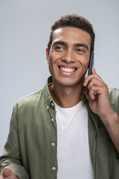 Varón joven guapo sonriendo hablando por su teléfono inteligente