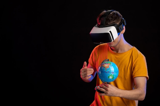 Varón joven jugando realidad virtual con globo sobre superficie oscura