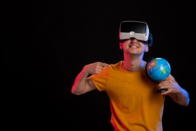 Varón joven jugando realidad virtual con globo sobre superficie oscura