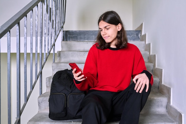 Varón joven sentado en las escaleras con smartphone