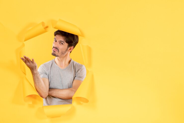 Foto varón joven sobre fondo de papel amarillo rasgado facial guapo interior