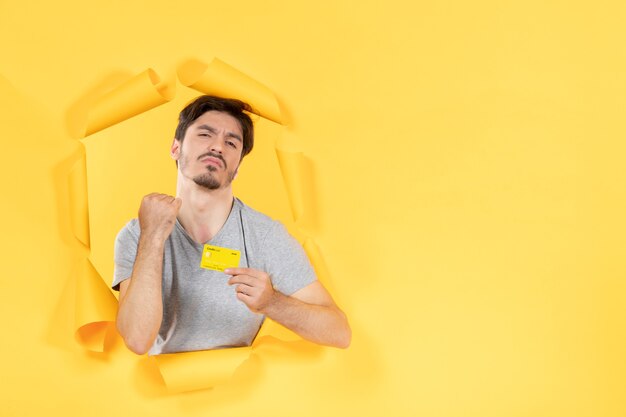 Varón joven con tarjeta de crédito en papel amarillo rasgado banco de compras de dinero de fondo