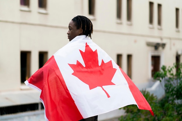 Un varón negro que sostiene una bandera de canadá al aire libre concepto de patriotismo e independencia