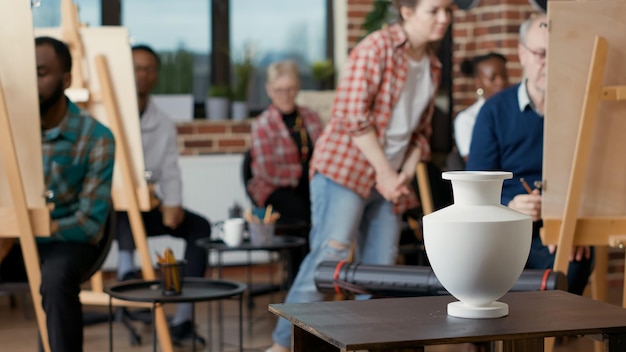 Vase auf dem Tisch, die als Inspirationsmodell für Studenten verwendet wird, um auf Leinwand zu zeichnen, um Zeichenfähigkeiten für das persönliche Wachstum im Kunstprogramm zu üben. Künstlerische Gestaltung zum Skizzieren auf Papier. Handschuss