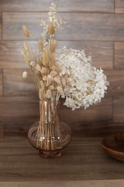 Vase mit Bouquet von getrockneten Hortensien Ährchen und Pflanzen Holztisch Herbst Wohnkultur