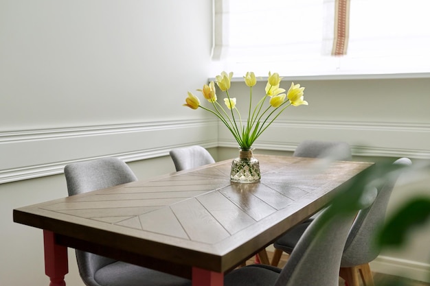 Vase mit einem Strauß gelber Tulpen auf einem Holztisch