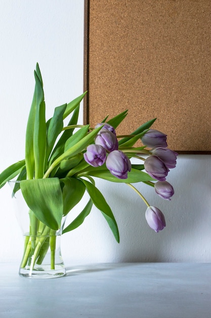 Vase mit lila Tulpenblüten und Holzbrett. Speicherplatz kopieren