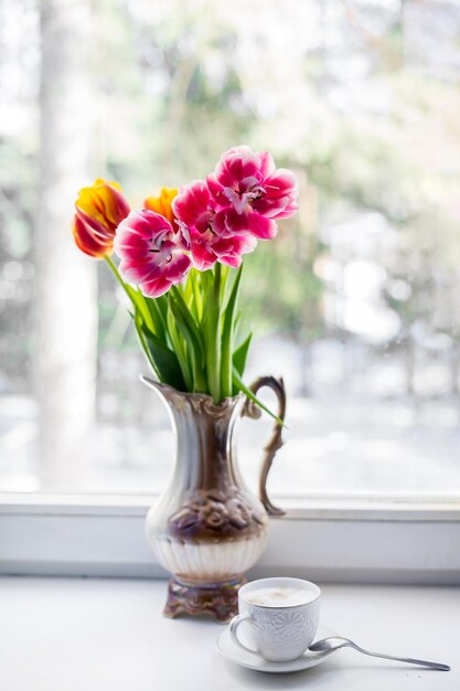 Vase voller Tulpen, die auf weißem Hintergrund am Fenster isoliert sind