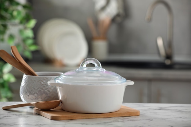 Vasijas de cerámica y utensilios de cocina sobre mesa de mármol blanco en la cocina