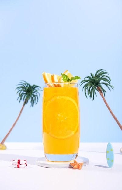 Foto vaso de 100 zumo de naranja con rebanadas de naranjas frutas en la playa de mar con arena blanca vacaciones de verano en el mar