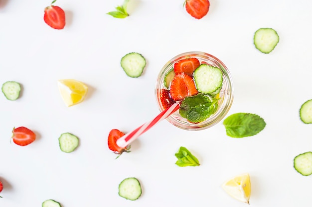 Un vaso de agua con la adición de fresas, pepino, menta y limón.