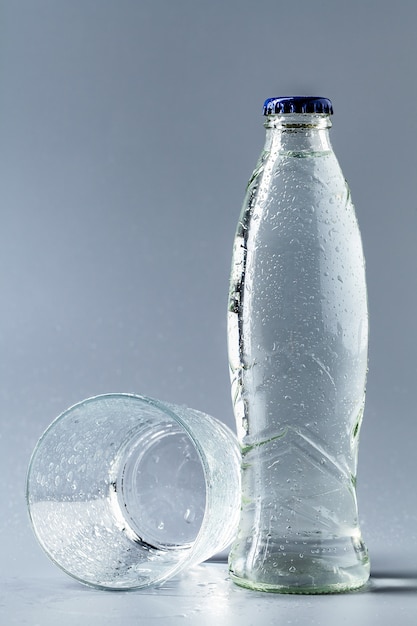 Vaso de agua con una botella en la mesa