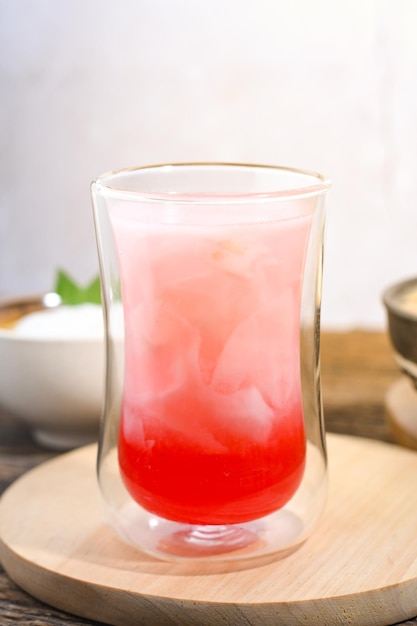 un vaso de agua de coco con jarabe rojo en una mesa de madera comida iftar de Ramadán