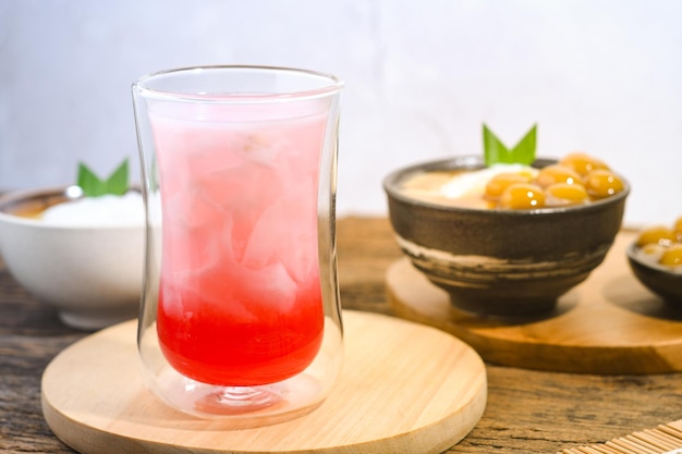 un vaso de agua de coco con jarabe rojo en una mesa de madera comida iftar de Ramadán