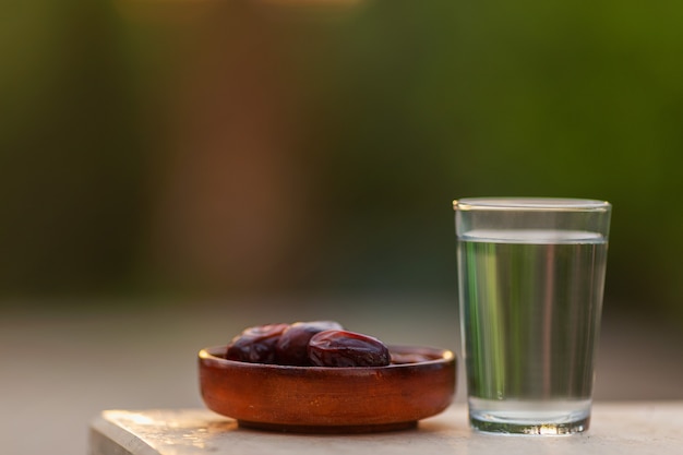 Vaso de agua y dátiles secos iftar en un plato listo para comer durante el tiempo iftar, religión islámica y ramadán