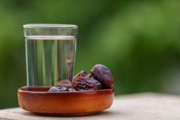 Vaso de agua y dátiles secos iftar en un plato listo para comer durante el tiempo iftar, religión islámica y ramadán