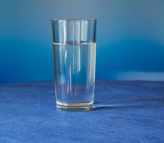 El vaso de agua está sobre el fondo azul de la mesa.