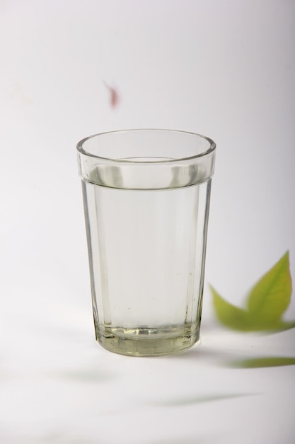 vaso con agua y un fondo claro con hojas de plantas