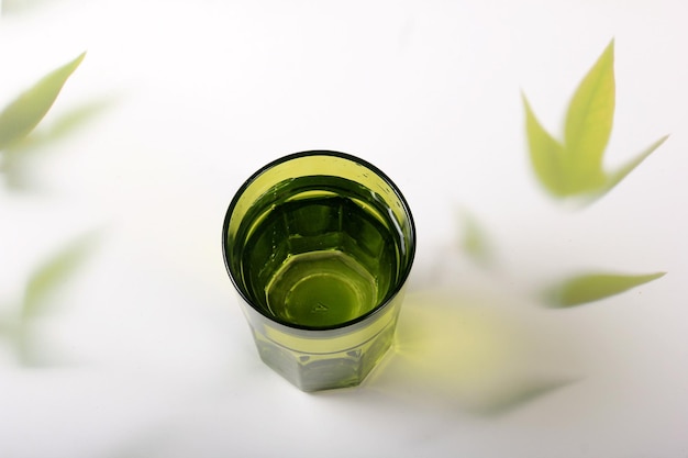 vaso con agua y un fondo claro con hojas de plantas