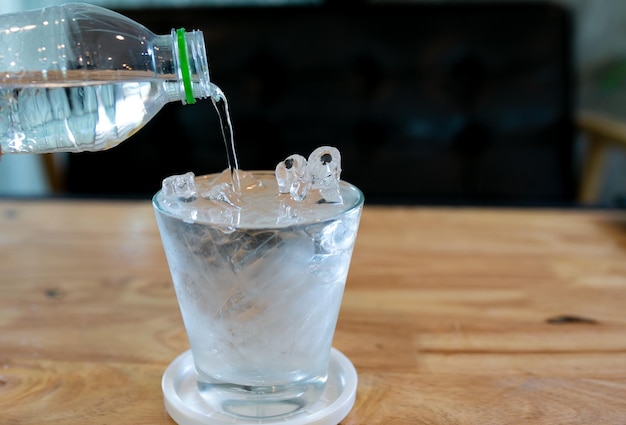 Vaso de agua fría y café fresco en la mesa de madera en el fondo de la cafetería