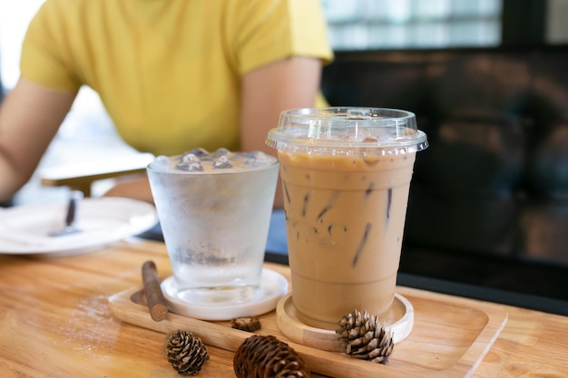 Vaso de agua fría y café fresco sobre una mesa de madera en el fondo de la cafetería.