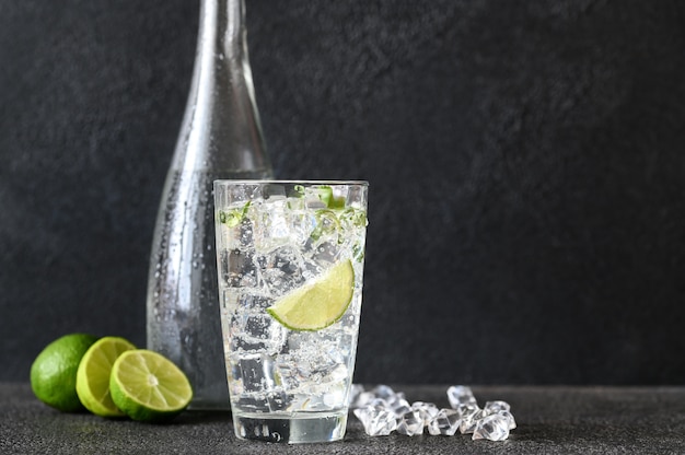 Vaso de agua con gas con cubitos de hielo y rodaja de limón