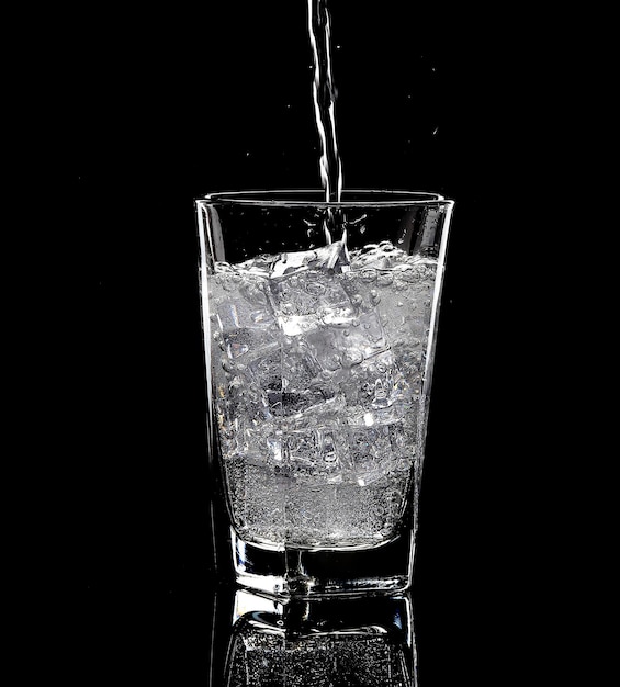 Vaso de agua con hielo en el fondo negro