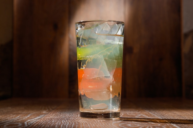 Vaso de agua con hielo en la mesa de madera.