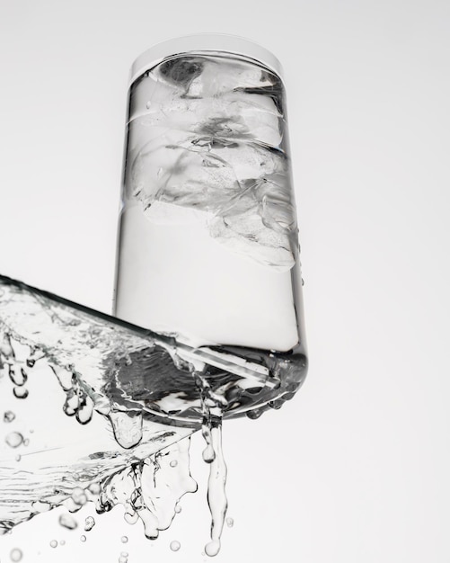 Vaso de agua con hielo sobre una mesa de cristal