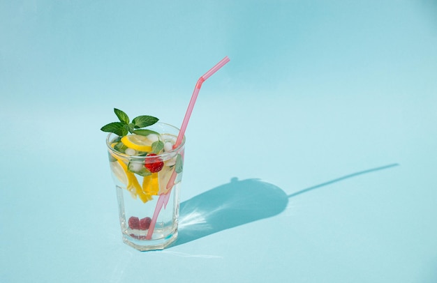 Vaso de agua con hojas de menta rodajas de limón frambuesas y cubitos de hielo Concepto de bebida fría o refresco Concepto de verano mínimo Espacio de copia