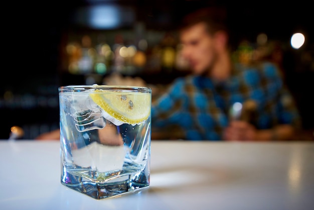 Un vaso con agua, limón y hielo en la barra.