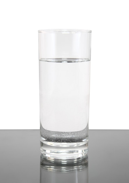 Vaso de agua limpia sobre fondo blanco-gris. Aislado