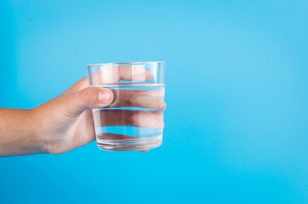 Vaso de agua en mano en azul