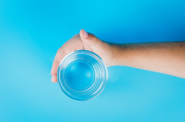 Vaso de agua en mano en azul