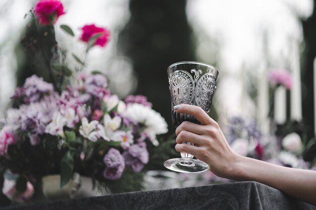 Vaso de agua en la mano de la mujer. Fondo de jardín y flores.