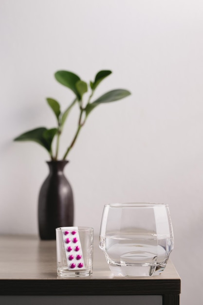 Un vaso de agua y medicina en la mesa de maderax9