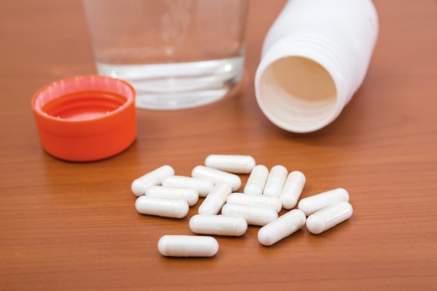 Vaso de agua y pastillas en una mesa de madera. Concepto de salud.