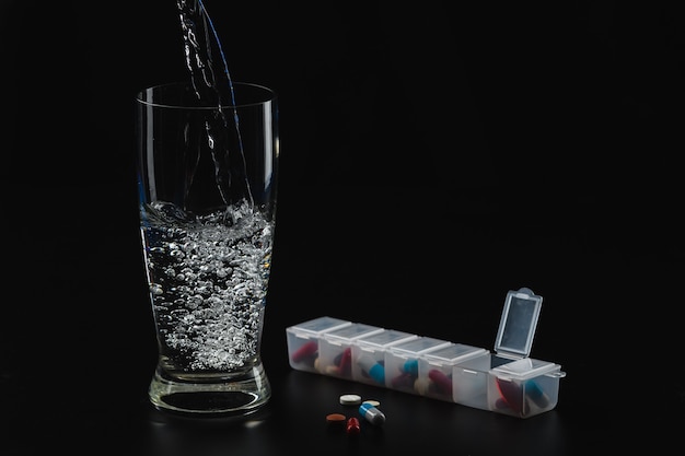 Un vaso de agua y pastillas.