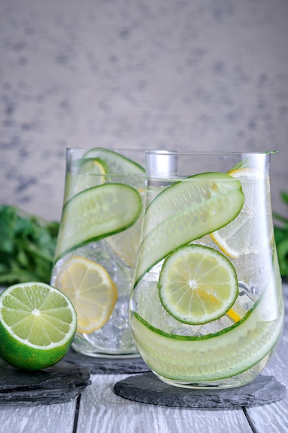 Vaso con agua de pepino de desintoxicación orgánica fresca sobre fondo gris