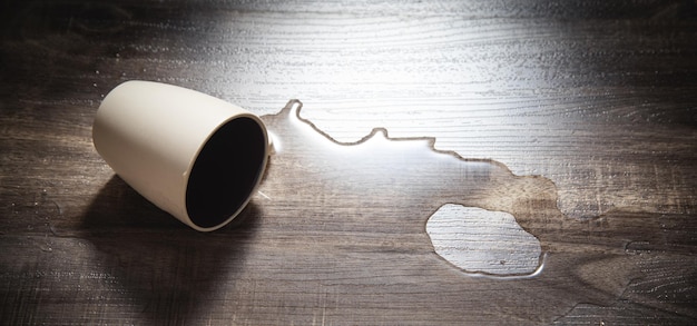 Vaso de agua potable caído al piso laminado