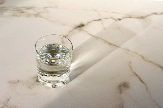Un vaso de agua potable purificada sobre una mesa de mármol. Copie el espacio para el texto.