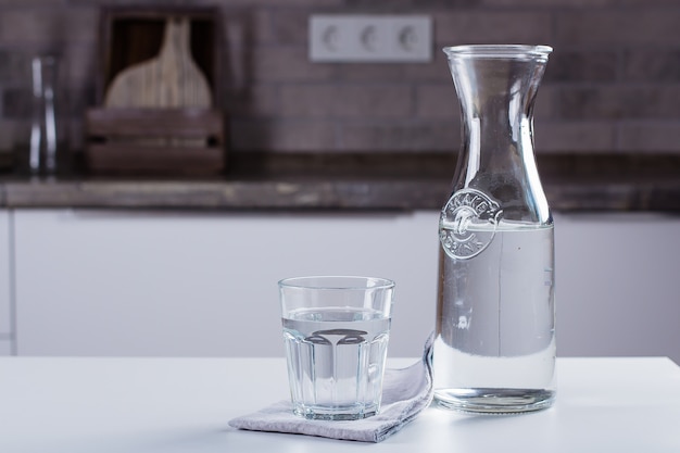 Vaso de agua pura y botella en la mesa de la cocina. Concepto limpio