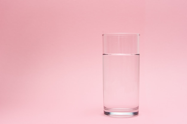 Vaso de agua sobre fondo rosa