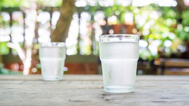 Un vaso de agua sobre una mesa de madera.